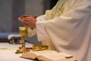 a priest blessing a communion cup. How to report clergy abuse at the diocese of Detroit.