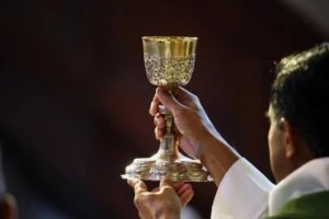 A priest holding up a cup. How to report clergy abuse at the Diocese of Kalamazoo.