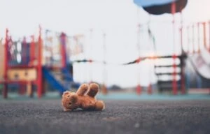 A teddy bear on the ground at a playground. What are legal options for survivors of child sex abuse?