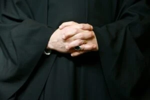 A clergy member with their hands folded on their lap. How to report clergy abuse at the Diocese of Marquette.