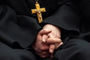 A clergy member with their hands folded on their lap. How to report clergy abuse at the Diocese of Saginaw.