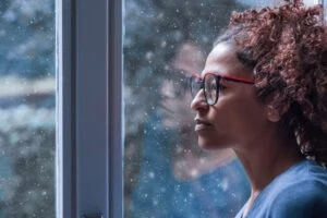 A woman looking out the window wondering if bystanders can be held liable in sexual abuse cases.