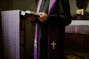 A priest holding a bible. The consequences of failing to monitor predator priests