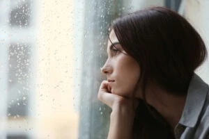 A woman looking out the window of a building wondering what is the bystander effect in abuse cases