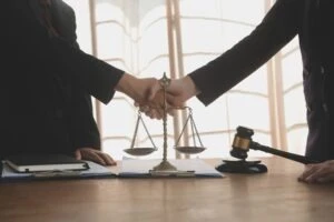 A sexual abuse lawyer and a client shaking hands behind the scales of justice.