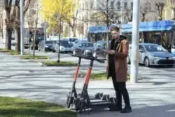 Young,man,unlocks,an,e scooter,with,his,mobile,phone