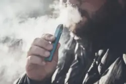 Man,smokes,new,vape,pod,system,,inhales,and,exhales,vapor