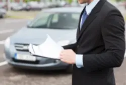 Man with clipboard in front of car