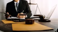 Lawyer writing behind scales of justice